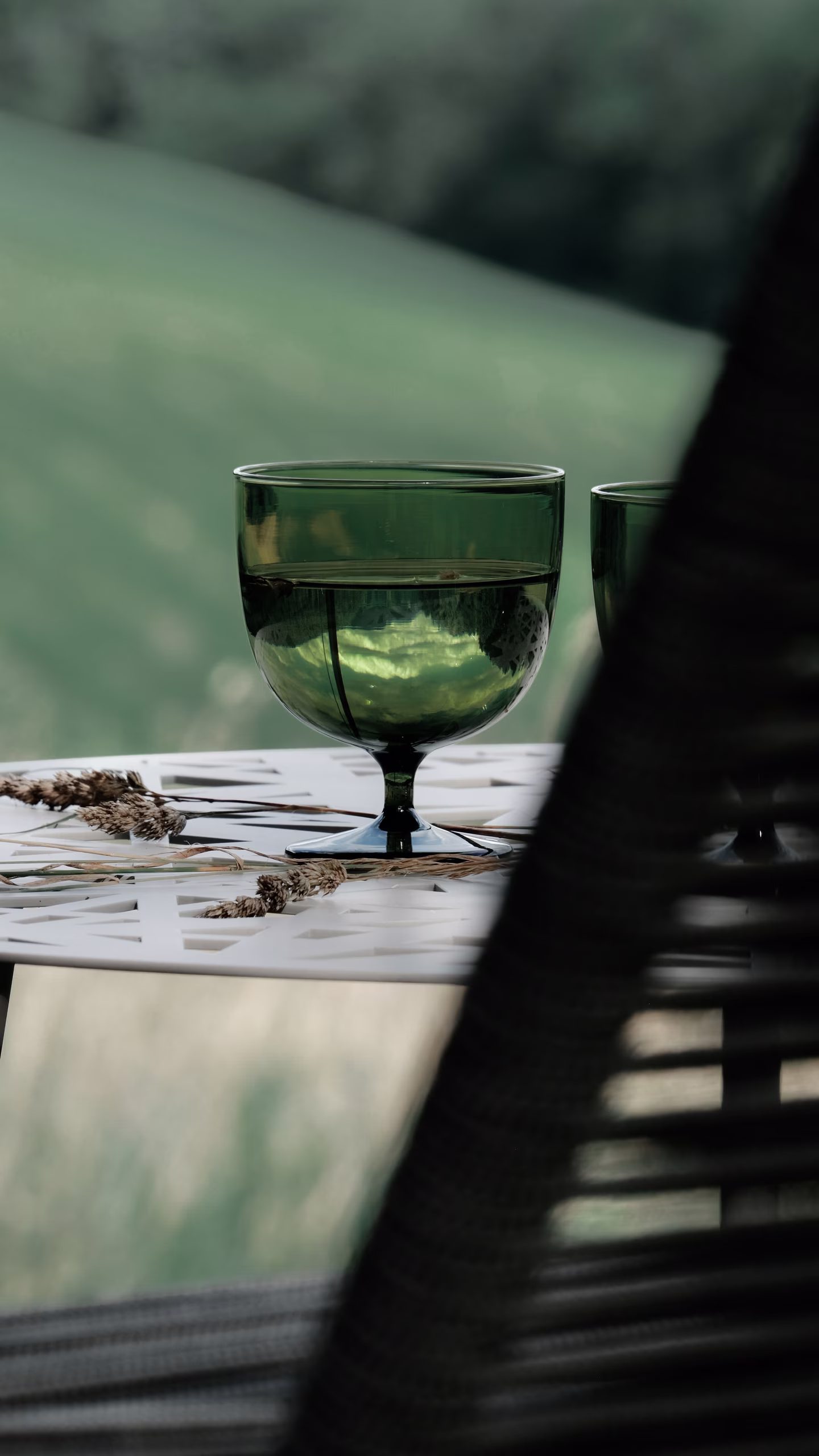 Verres design sur une table en terrasse face à un paysage alpin, moment de détente paisible lors d'un séjour SNUUG, hôtellerie éphémère de luxe en Suisse.