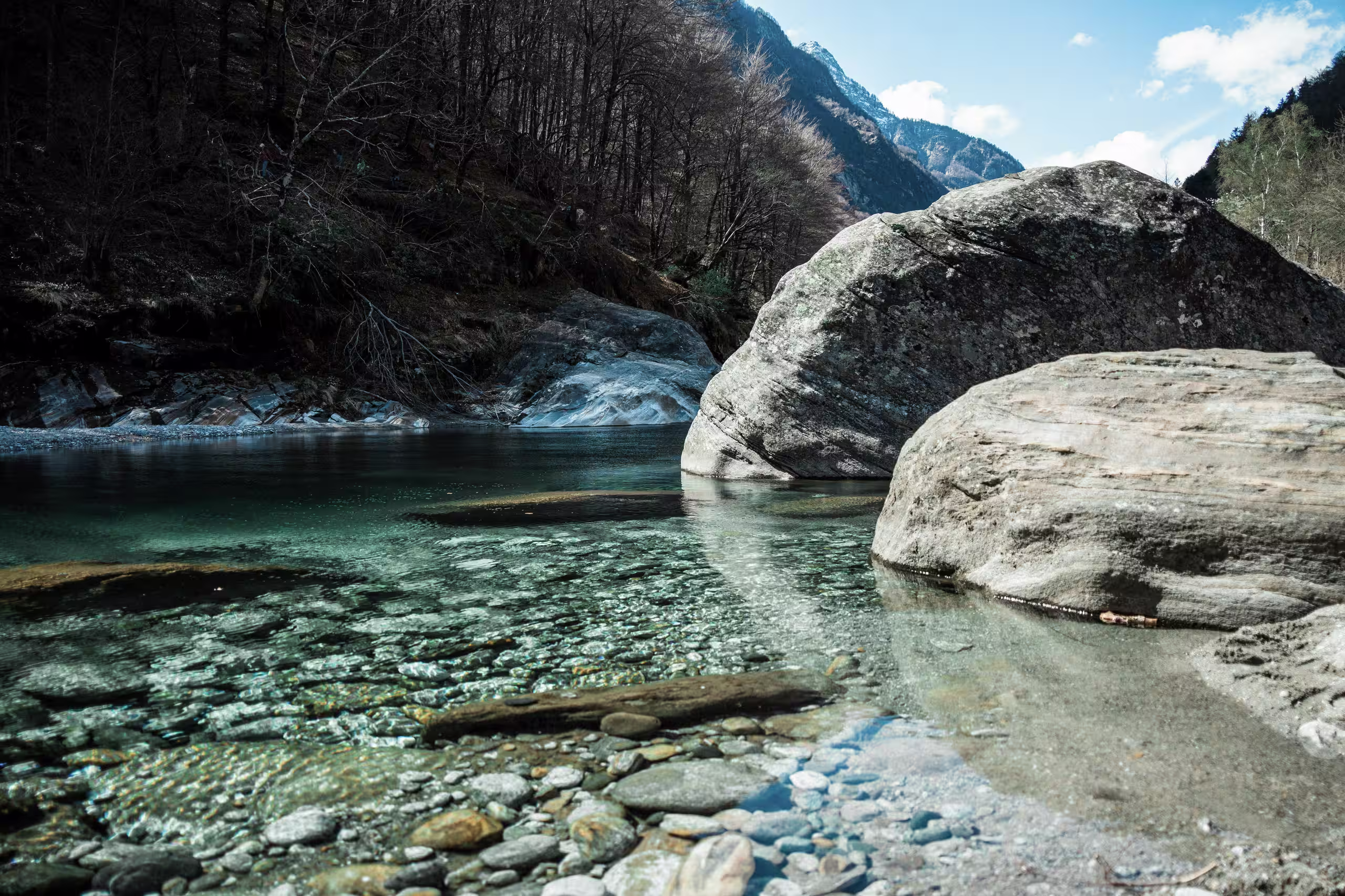Eau cristalline d'une rivière alpine entourée de rochers, soulignant l'engagement de SNUUG pour un tourisme durable sans empreinte.