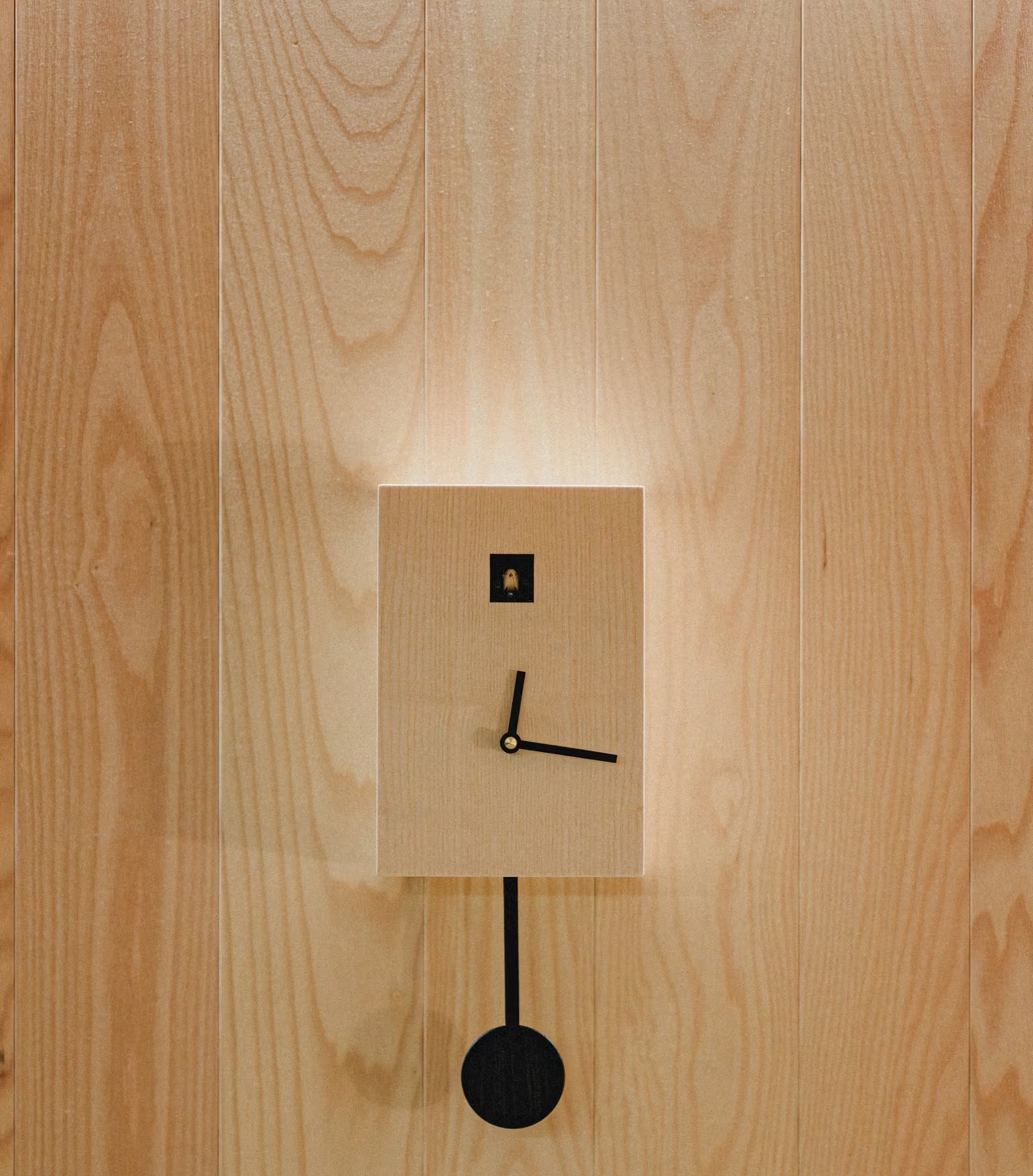 Minimalistische Design-Wanduhr an einer Naturholzwand, ein schlichtes Dekordetail, das den Lebensstil und modernen Komfort in einer mobilen SNUUG-Suite in der Schweiz veranschaulicht.