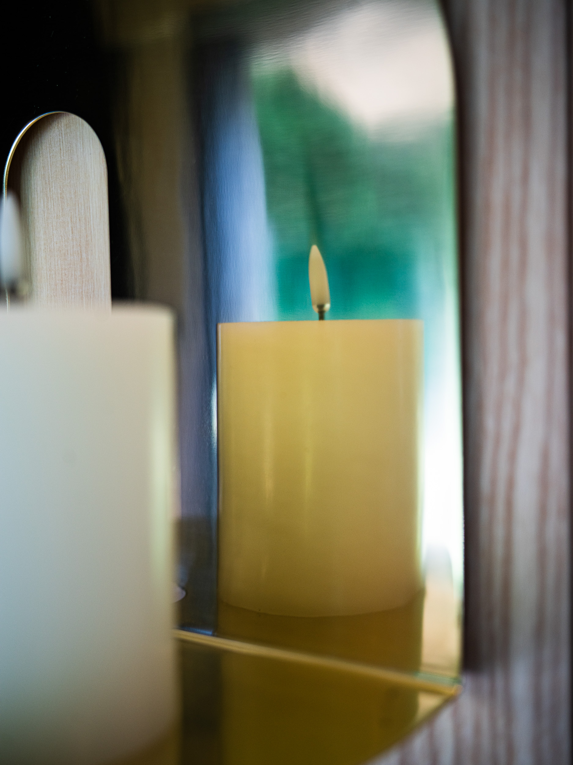 Atmosfera avvolgente con candele e orologio di design su una parete in legno naturale, il comfort poetico di un soggiorno SNUUG, hotel eco-responsabile itinerante.