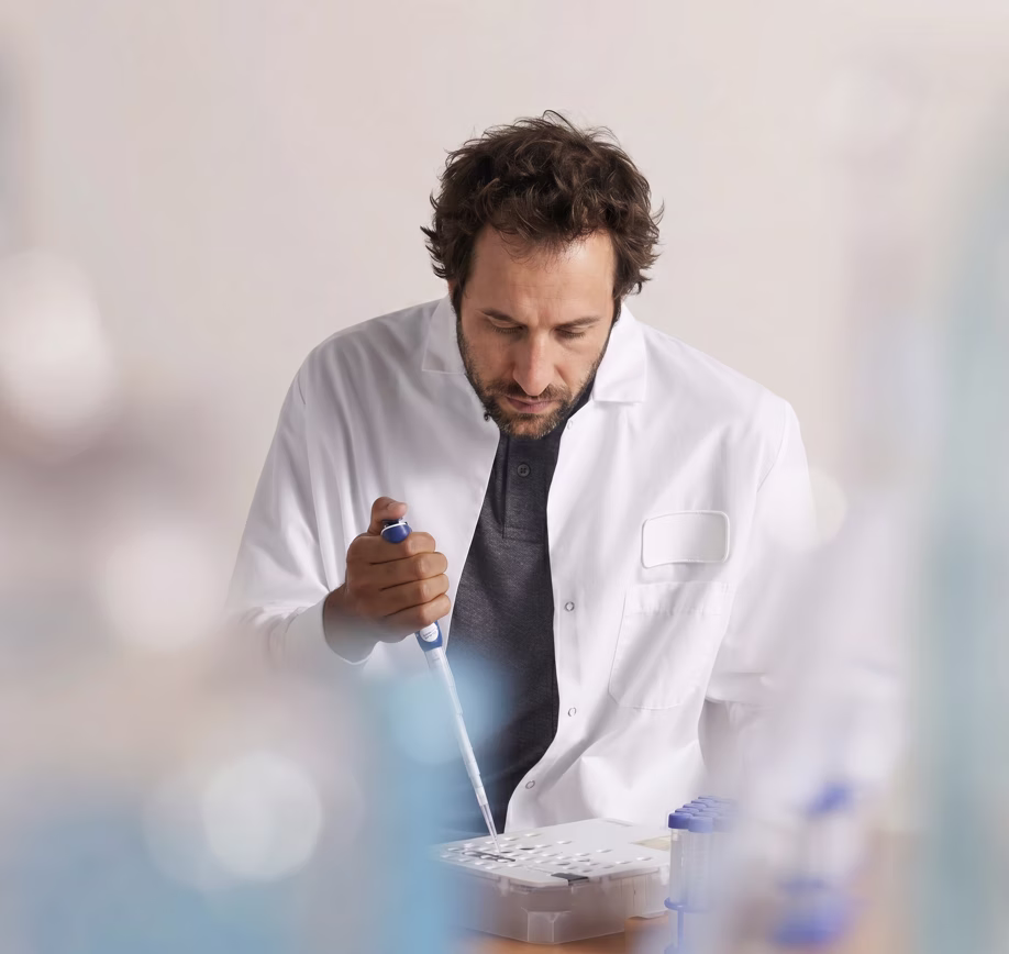 Biologiste en blouse blanche pipetant des échantillons au laboratoire