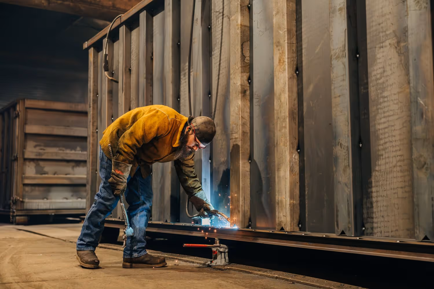 A welder welding the side posts of a roll off container