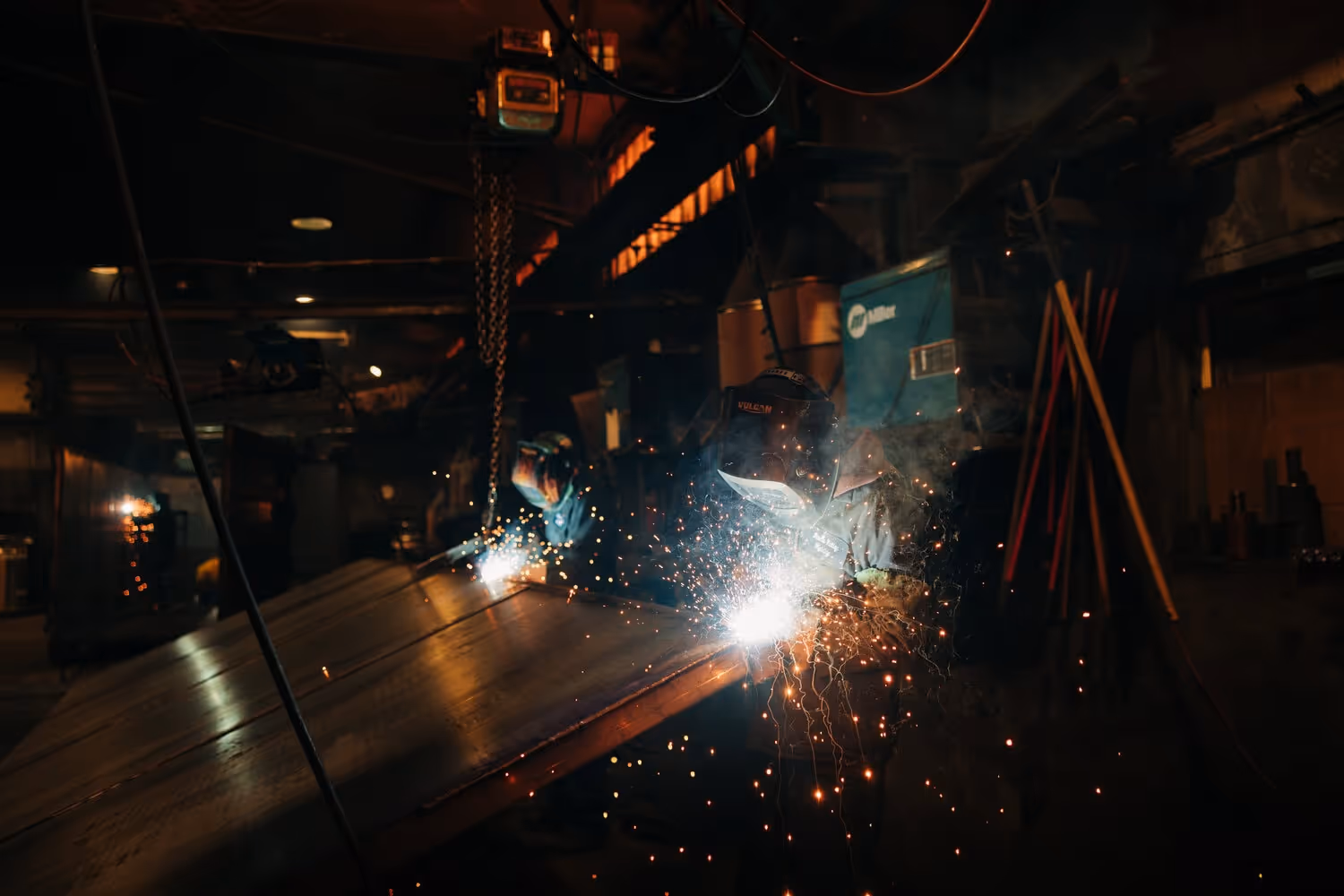 Two welders welding a roll off container