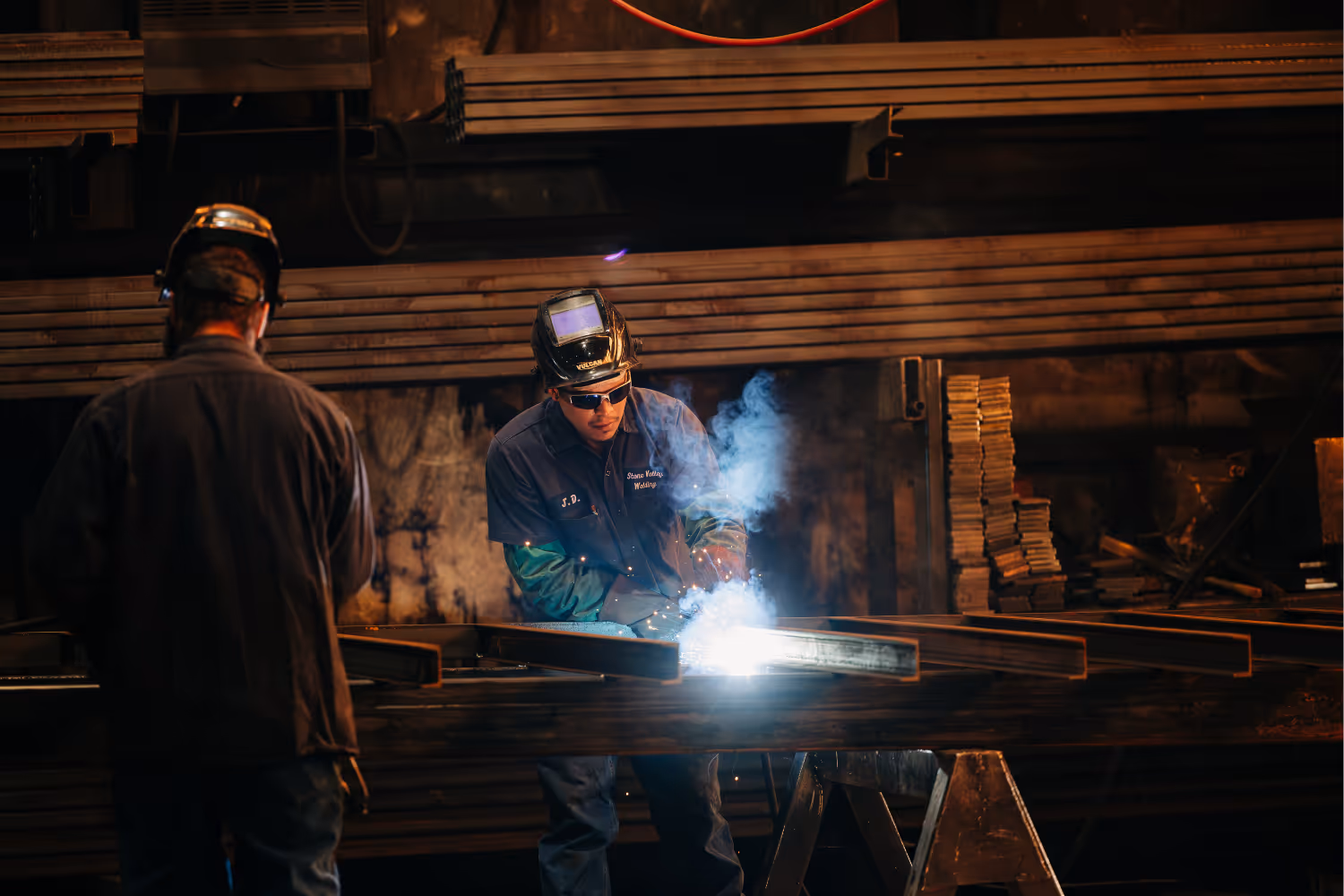 A welder welding a roll-off container floor cross pieces