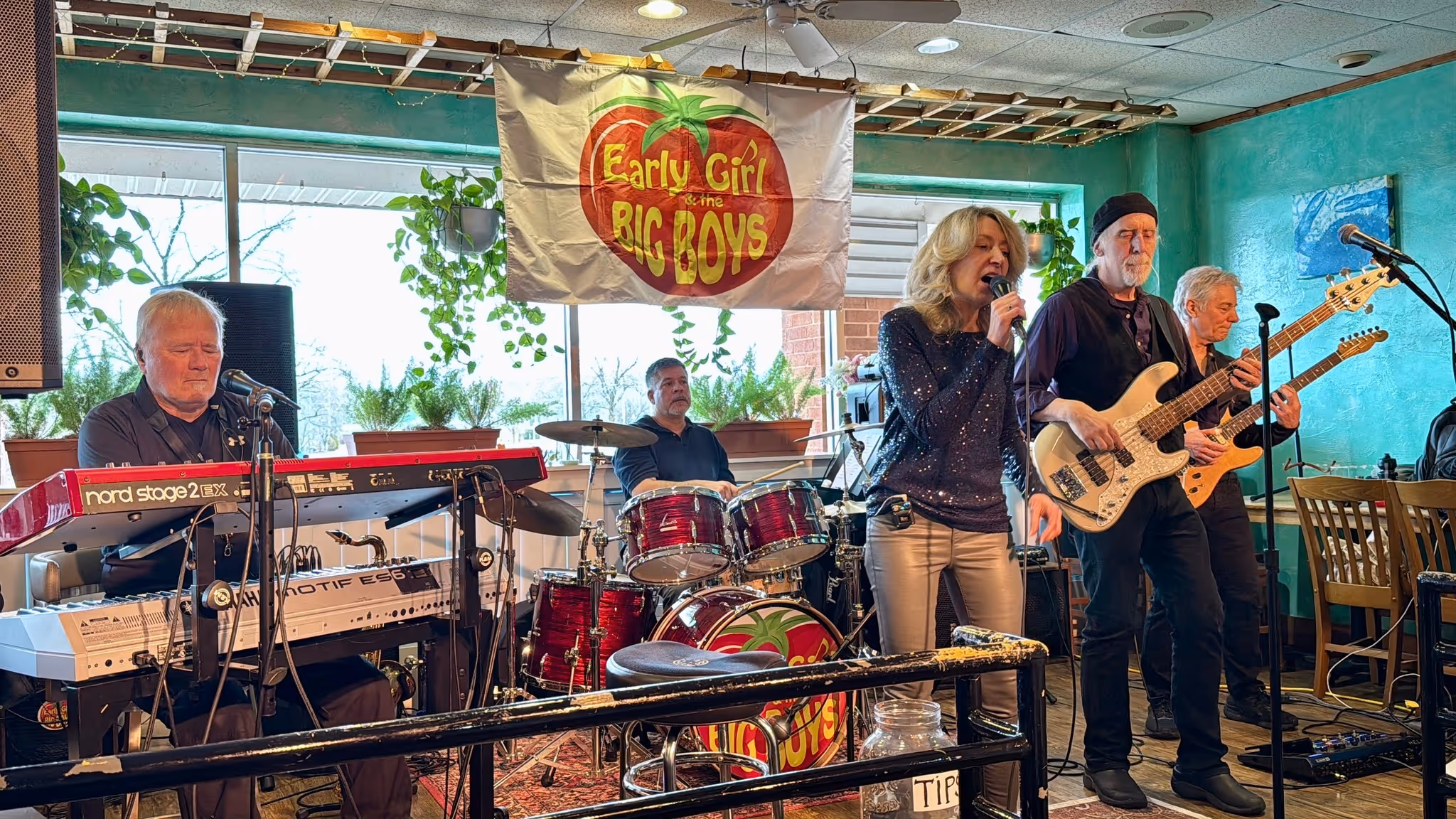 Five-member band Early Girl & the Big Boys performing indoors with keyboard, drums, bass, guitar, and vocals.