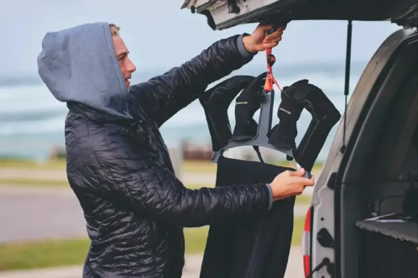 A man in a black jacket is putting items in the back of a truck
