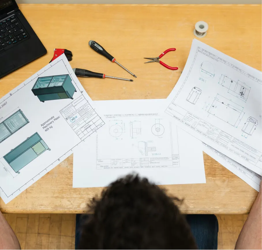 A person sitting at a table with some drawings and tools