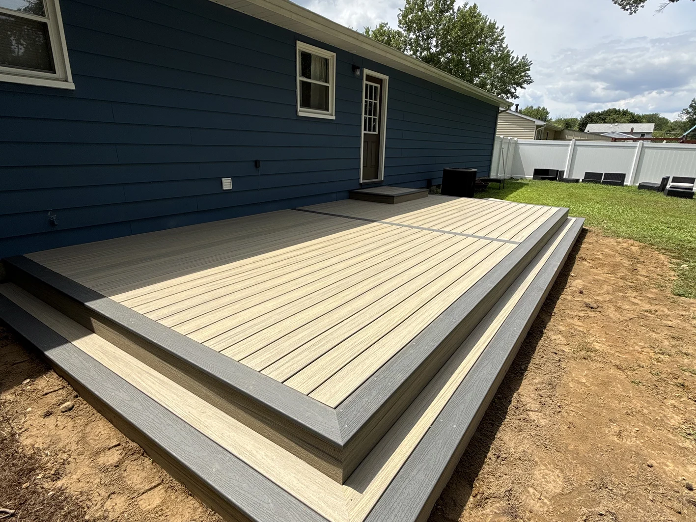 Modern low-profile composite deck with gray trim attached to a blue house.