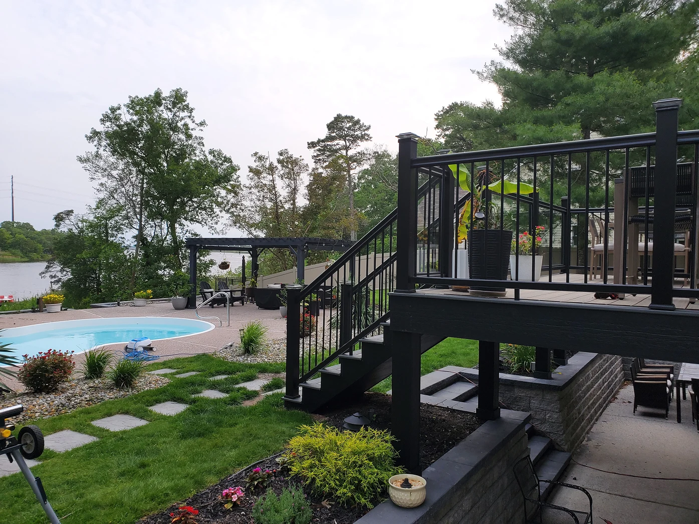 Black-railed deck beside landscaped yard with pool and patio area.