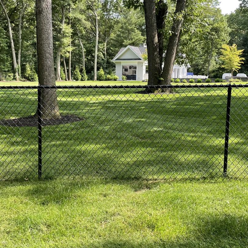 Raised backyard deck with white posts, black balusters, and wooden stairs.