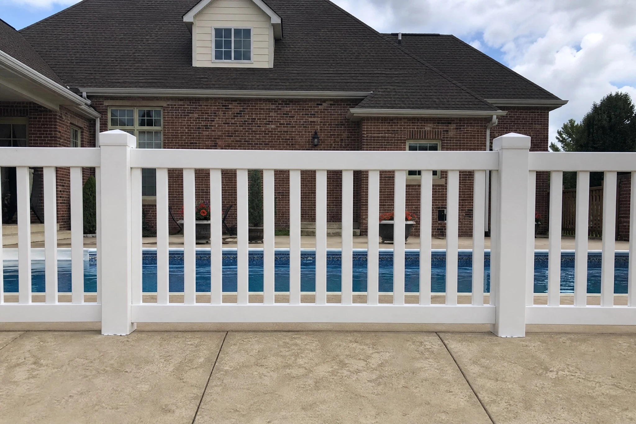 Outdoor deck with dining furniture overlooking a backyard pool and pergola.