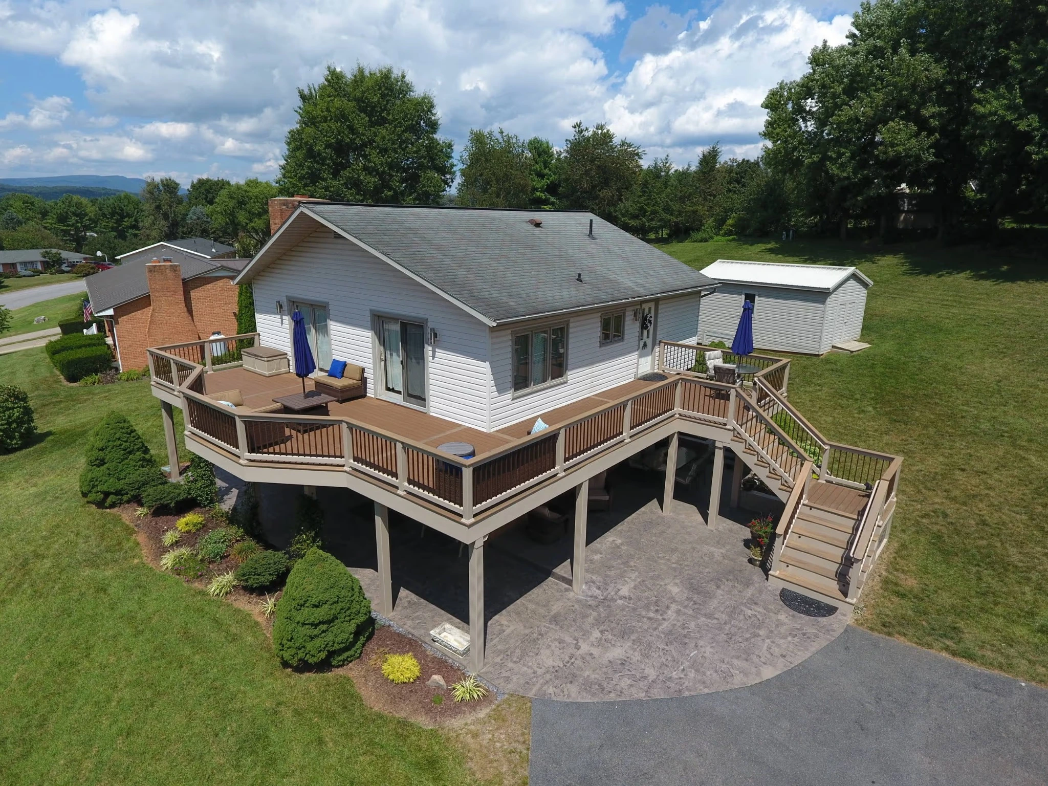 Large raised wraparound backyard deck with railings and stairs by Tri-State Fence & Deck.