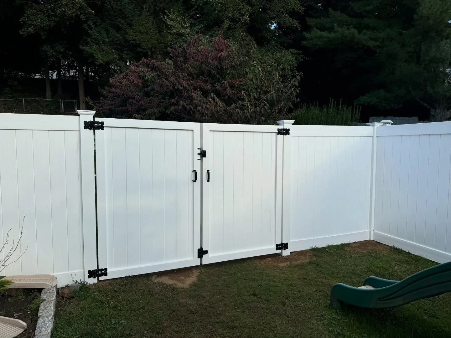 White vinyl privacy fence with a double gate supported by sturdy posts in a New Jersey backyard.