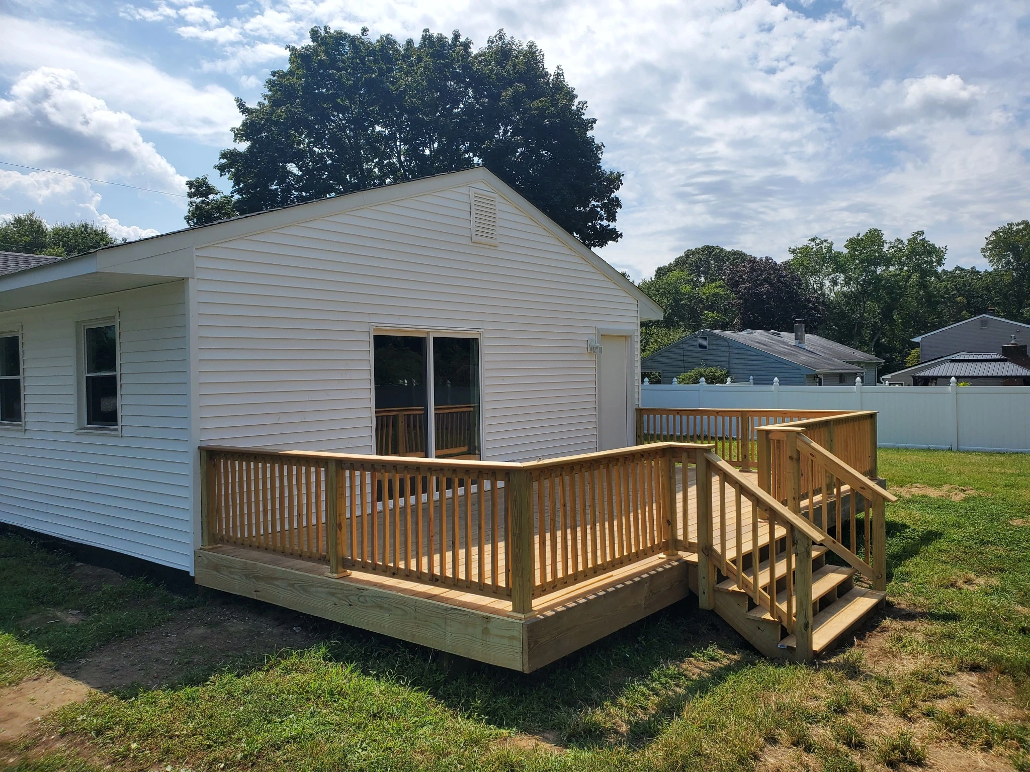 Pressure-treated wood deck with stairs and railings built beside a home as part of a permitted deck project.