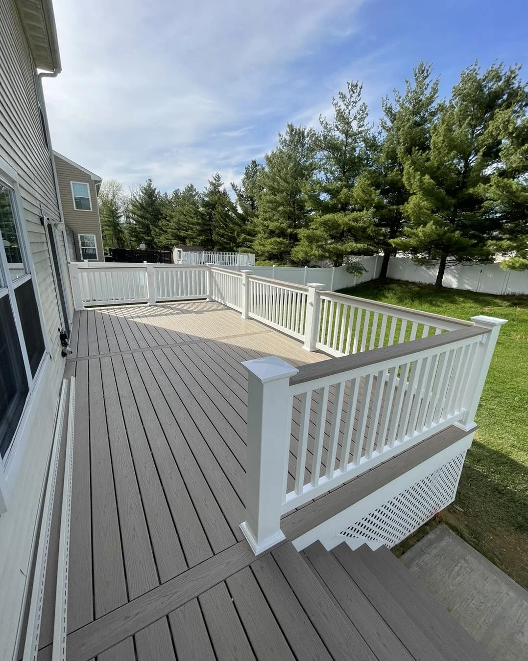 Composite backyard deck with white vinyl railings designed from a professional deck plan.