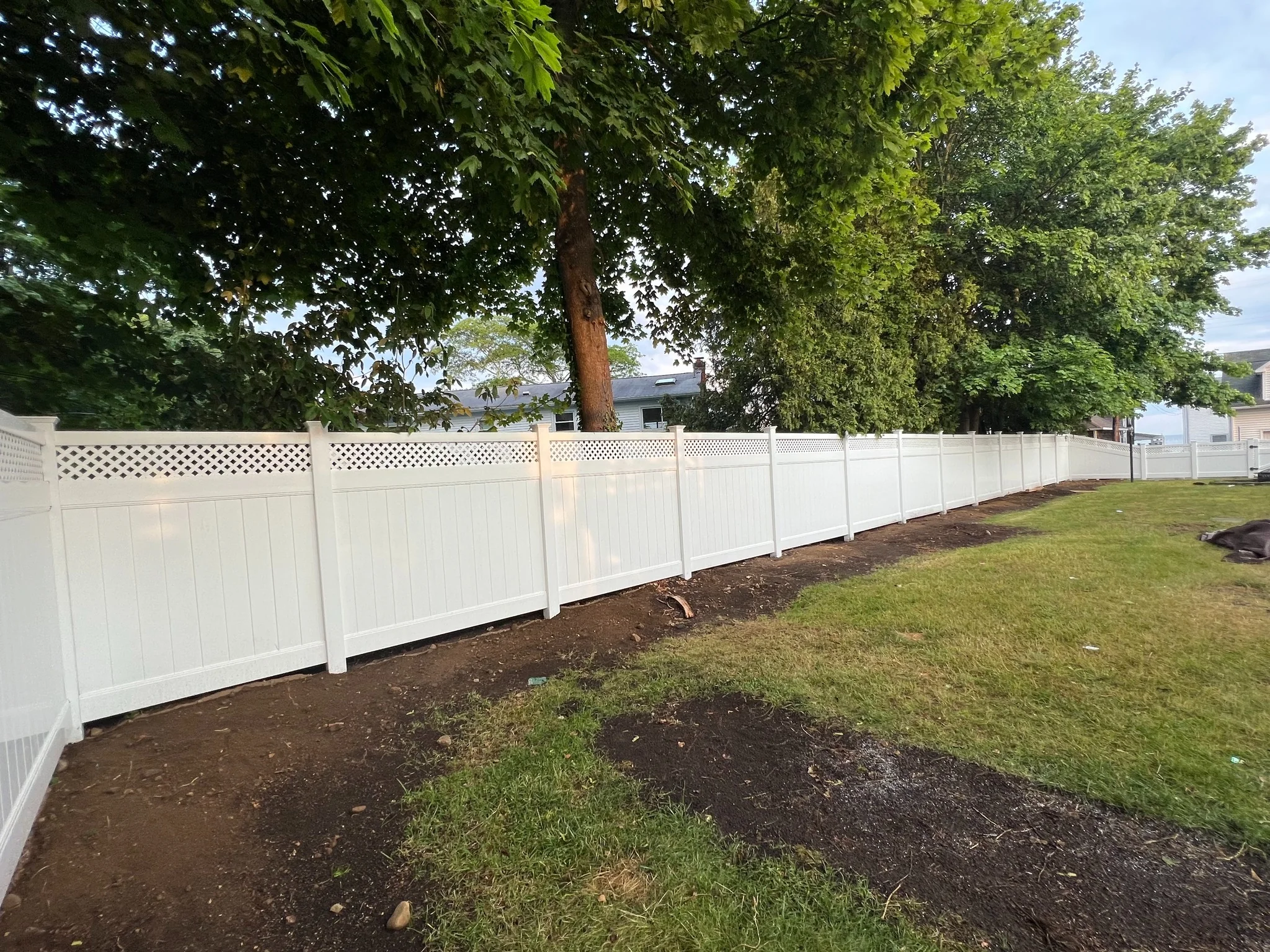 Tan and white vinyl privacy fence enclosing a residential backyard.
