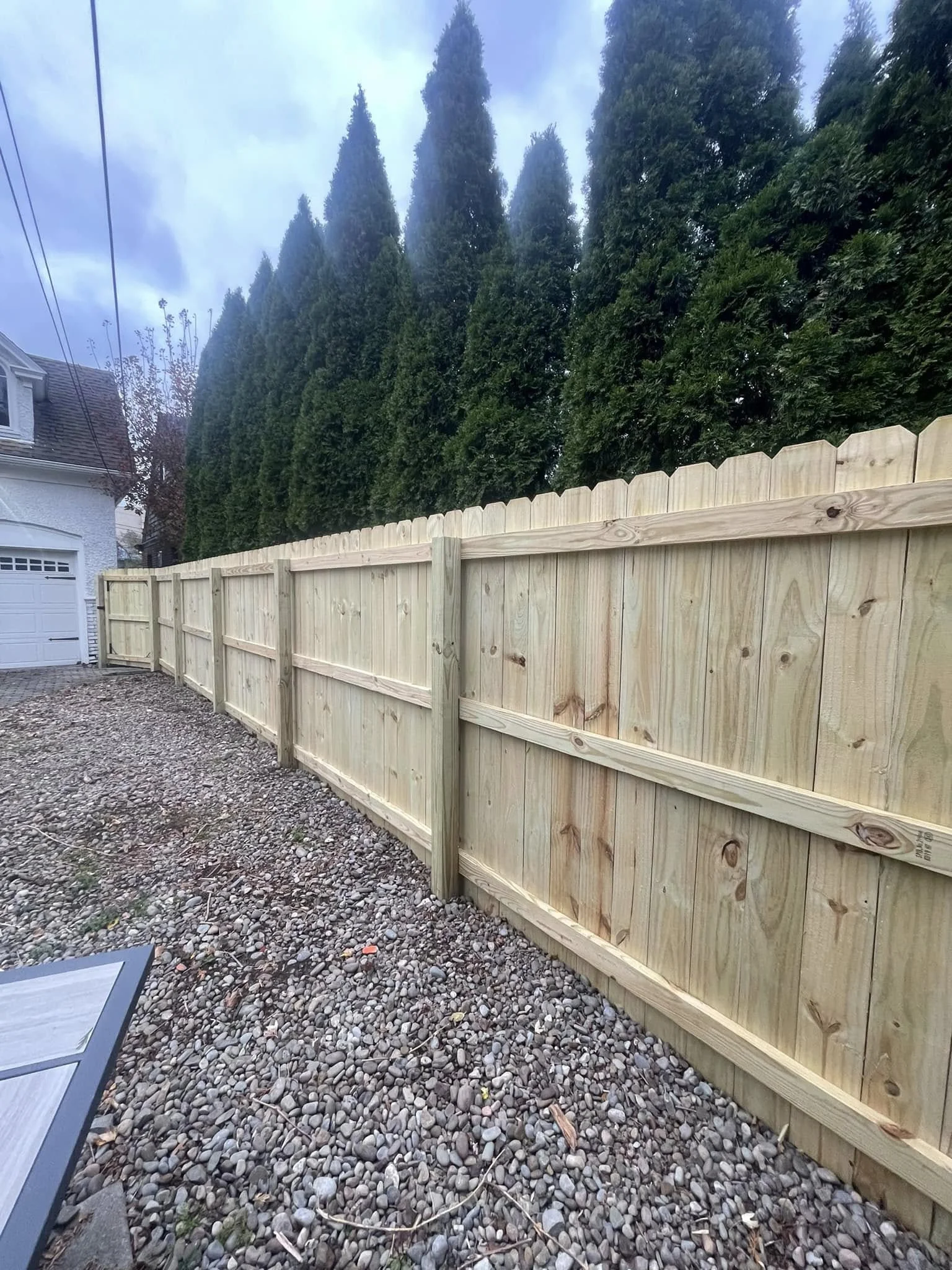 Pressure-treated pine privacy fence beside a gravel-covered backyard.