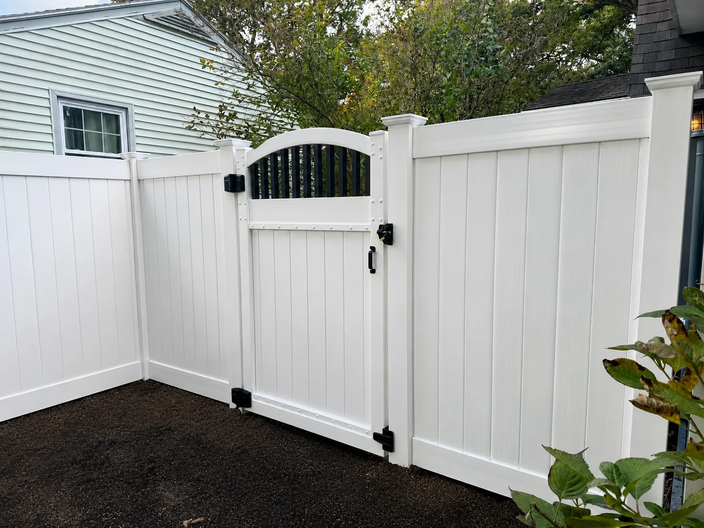 White vinyl privacy fence installed along a freshly cleared backyard in Delaware.