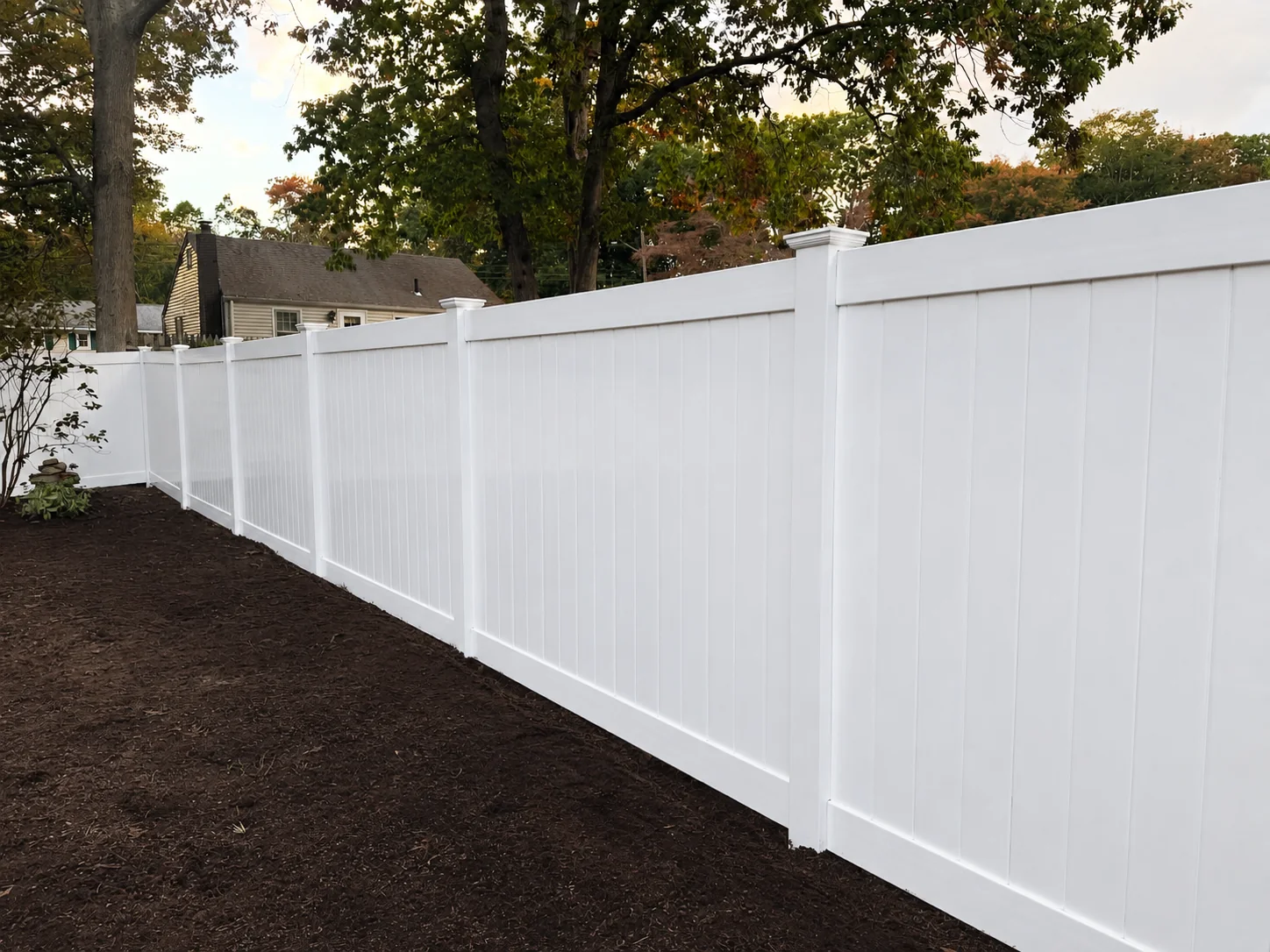 White vinyl privacy fence gate with black hardware beside a Delaware home.