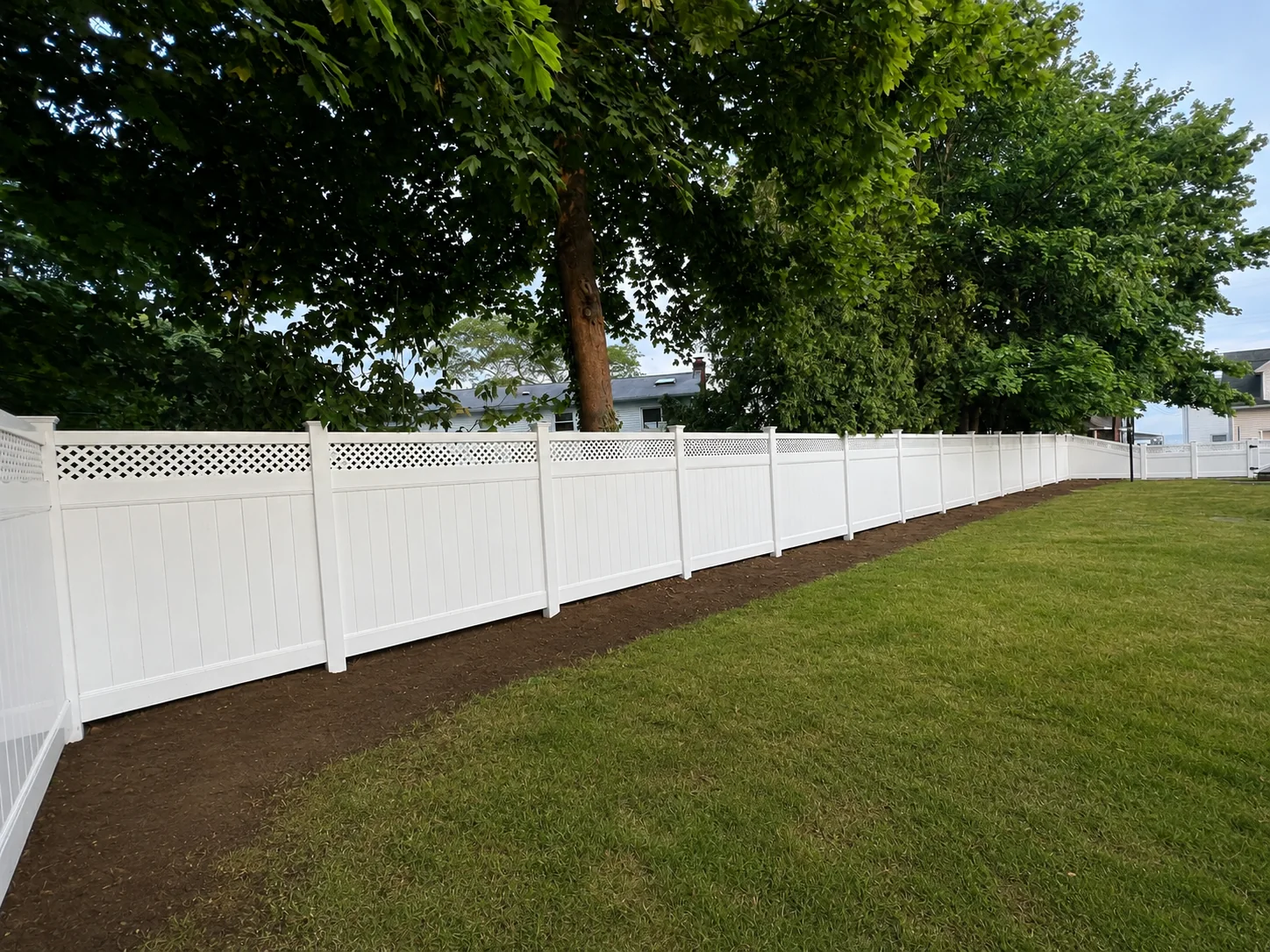 White vinyl privacy fence with lattice top enclosing a tree-lined yard in New Castle County, DE.