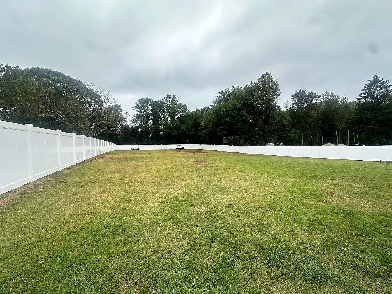 White vinyl privacy fence surrounding a large open lawn in Harrison Township, NJ.