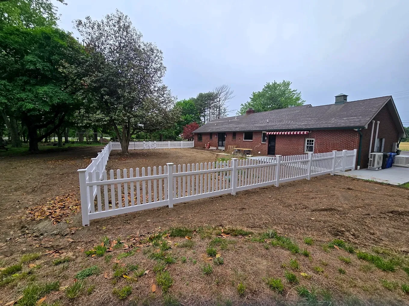 White vinyl picket fence enclosing a residential yard in Harrison Township, NJ.