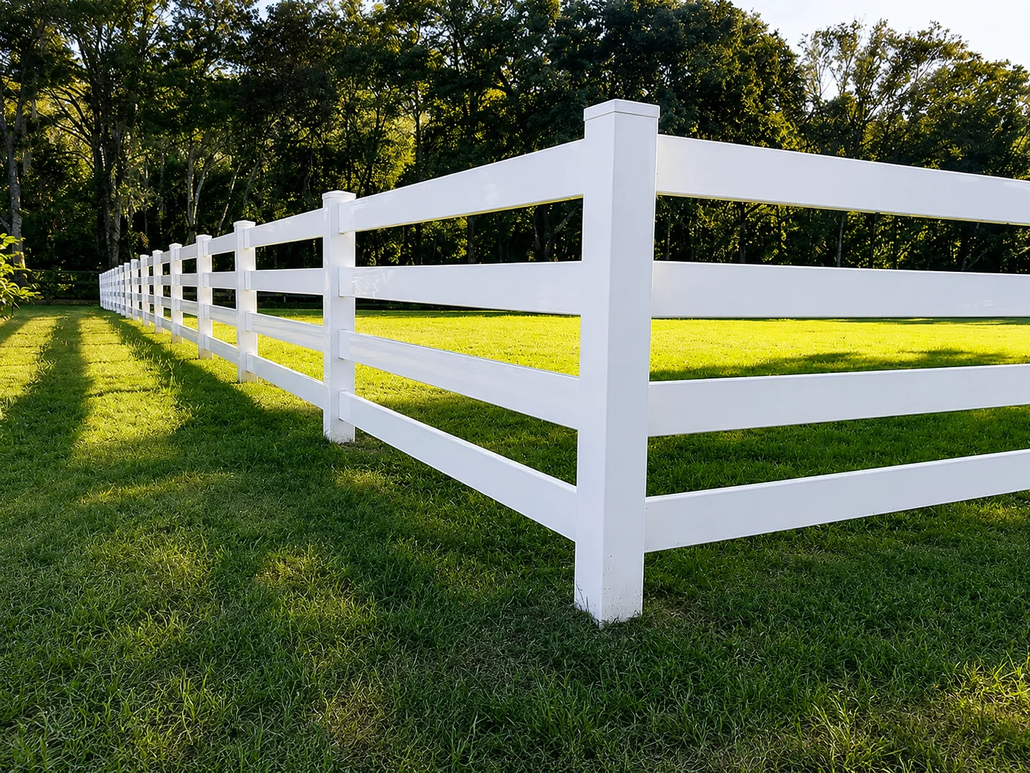 White vinyl ranch rail fence bordering a grassy property in Harrison Township, NJ.