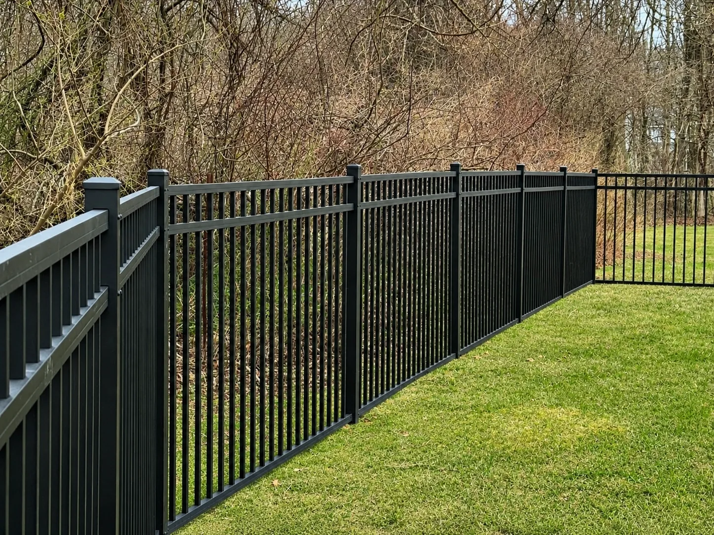 Black aluminum fence installed along a wooded residential property in Chester County, PA.