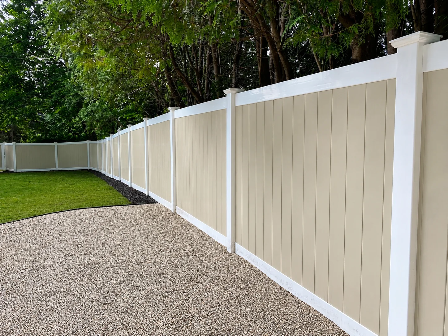Two-tone vinyl privacy fence with white posts enclosing a wooded backyard in Chester County, PA.