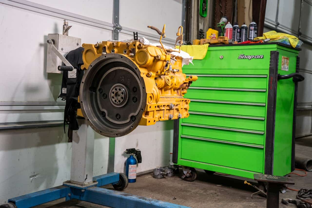 Engine rebuild with a heavy-duty diesel engine mounted on a stand beside a green Snap-on tool chest.
