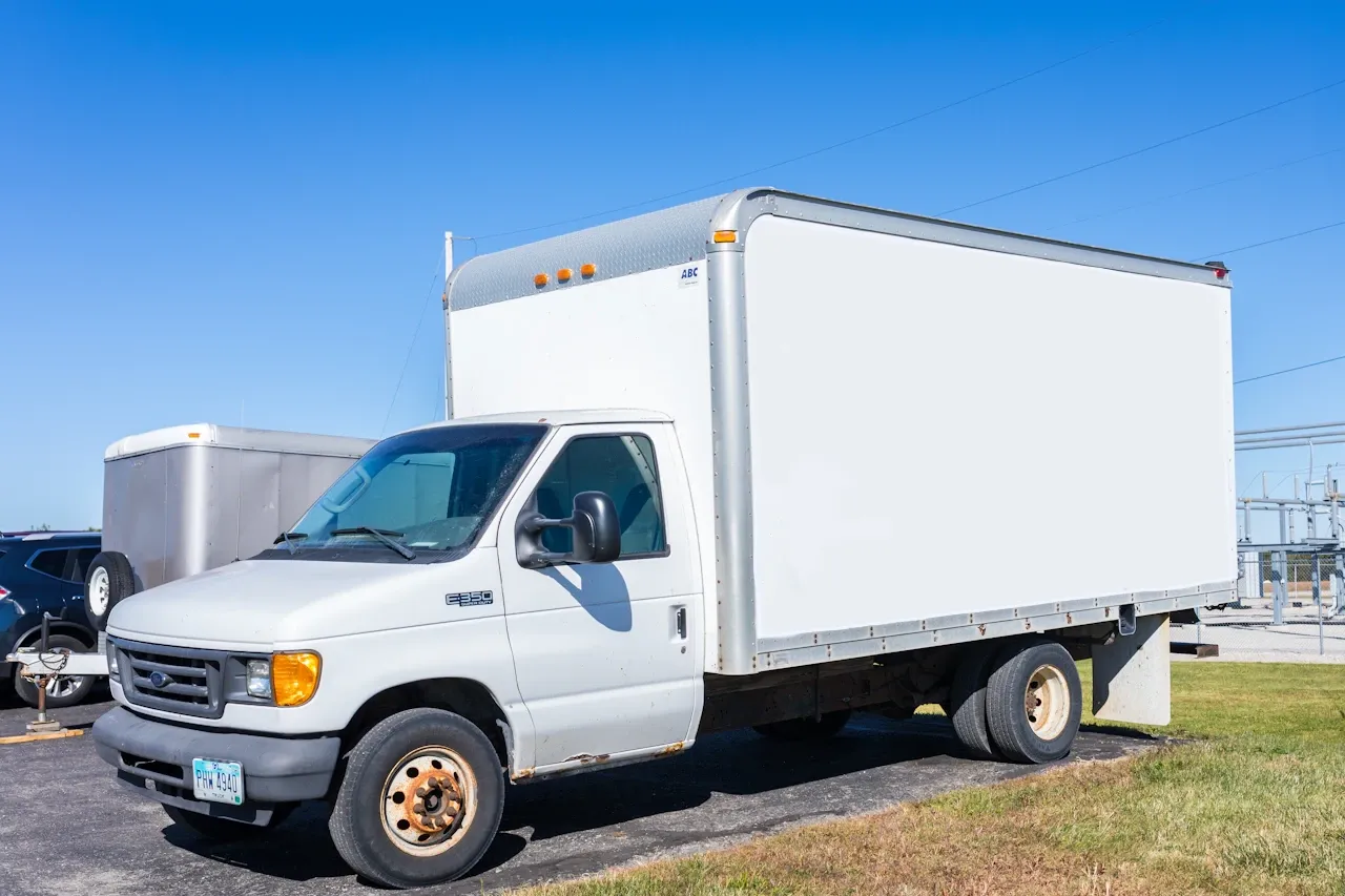 Box truck service for a white Ford E-350 commercial vehicle with an ABC cargo body parked outside a repair facility.