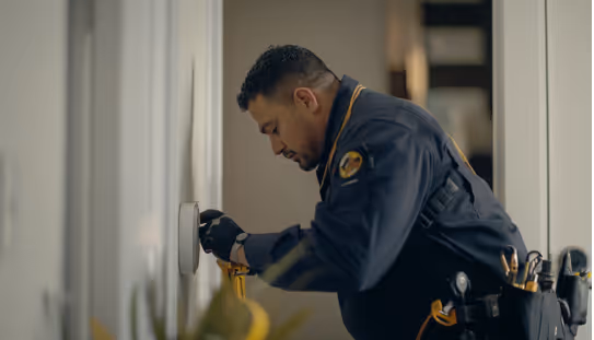 A heating and air conditioning technician repairing a thermostat.