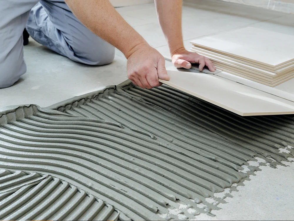 A worker installing tile on the floor.