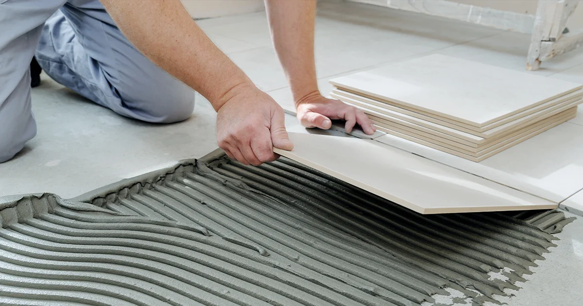 A worker installing tile on the floor.
