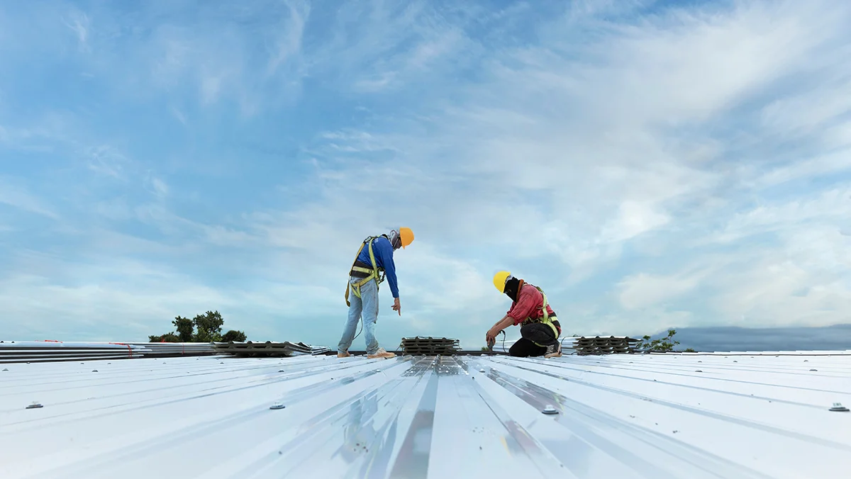 Two roofers working on the roof of a commercial building.