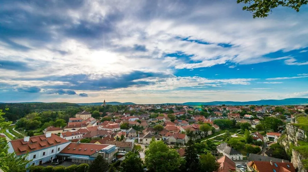 Panoramic view of a town with red-roofed houses under a partly cloudy sky.