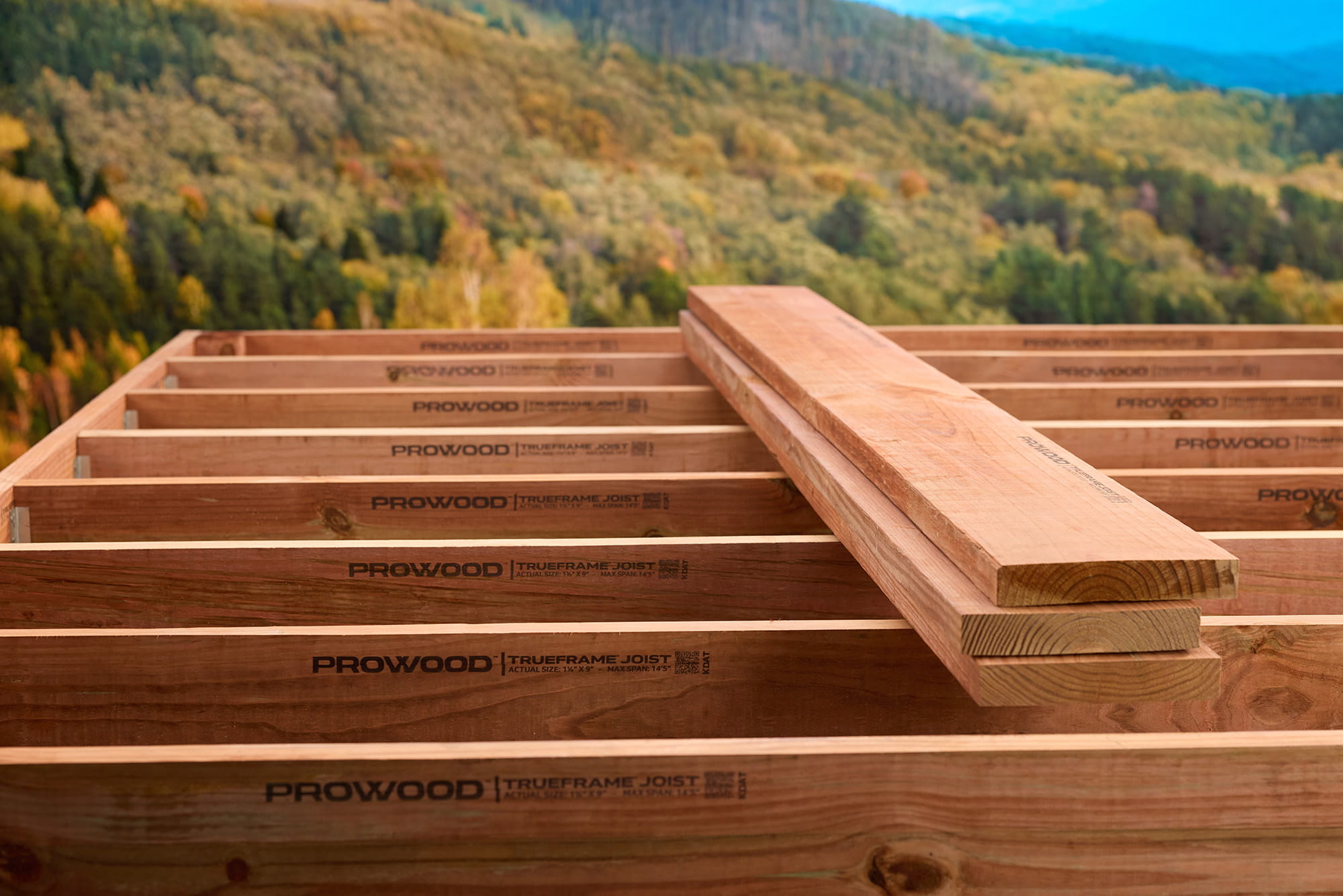 A stack of TrueFrame Joists on top of a deck frame over looking the mountains.