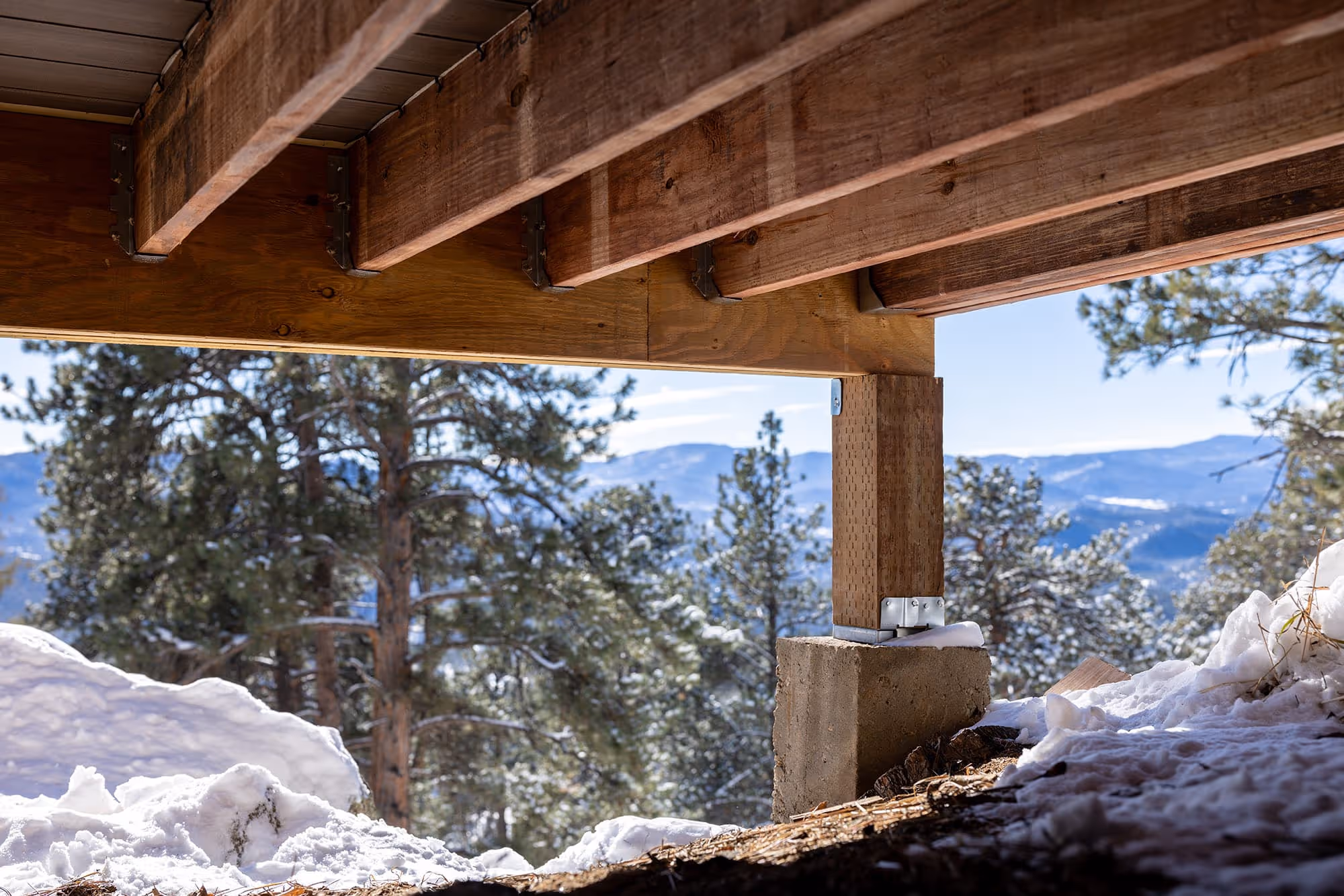 The underside of a deck in winter built with TrueFrame Joists overlooking the mountains.