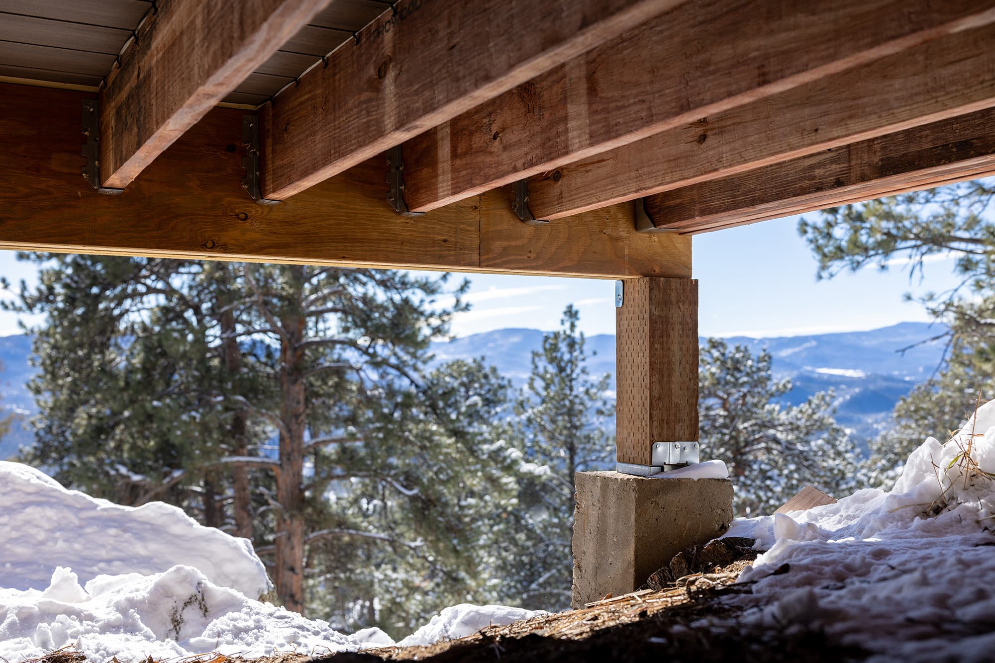 The underside of a deck in winter built with TrueFrame Joists overlooking the mountains.