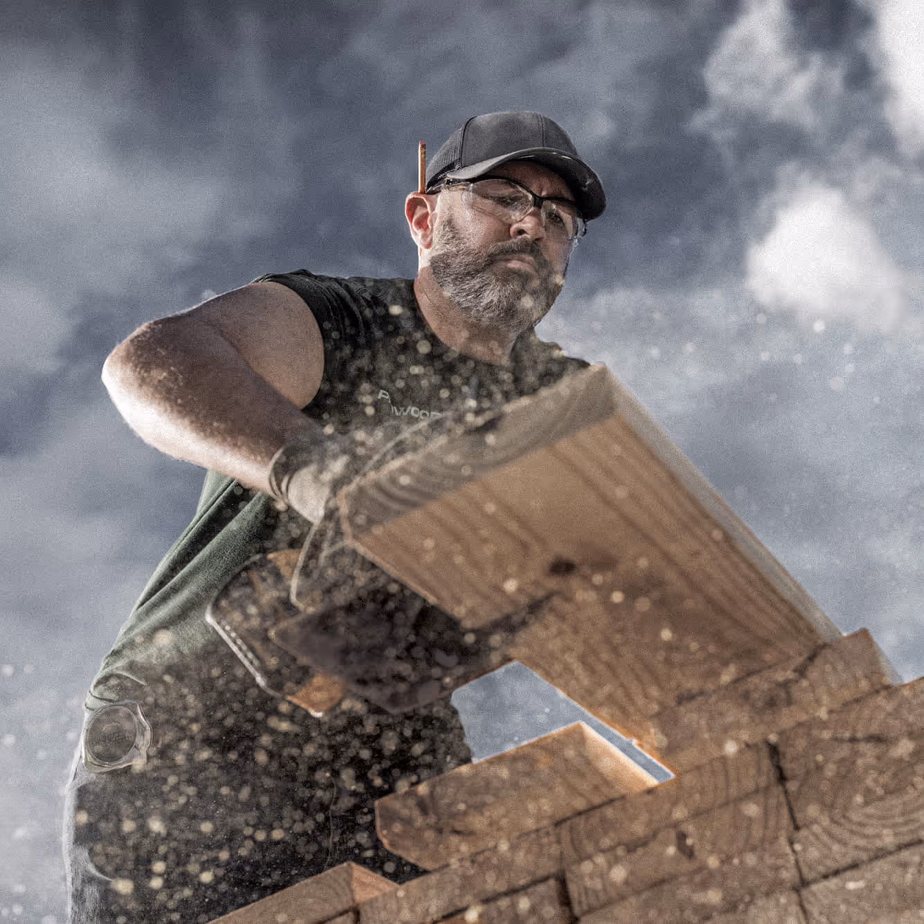 A person using a circular saw to cut the end off a deck board, shot from below.