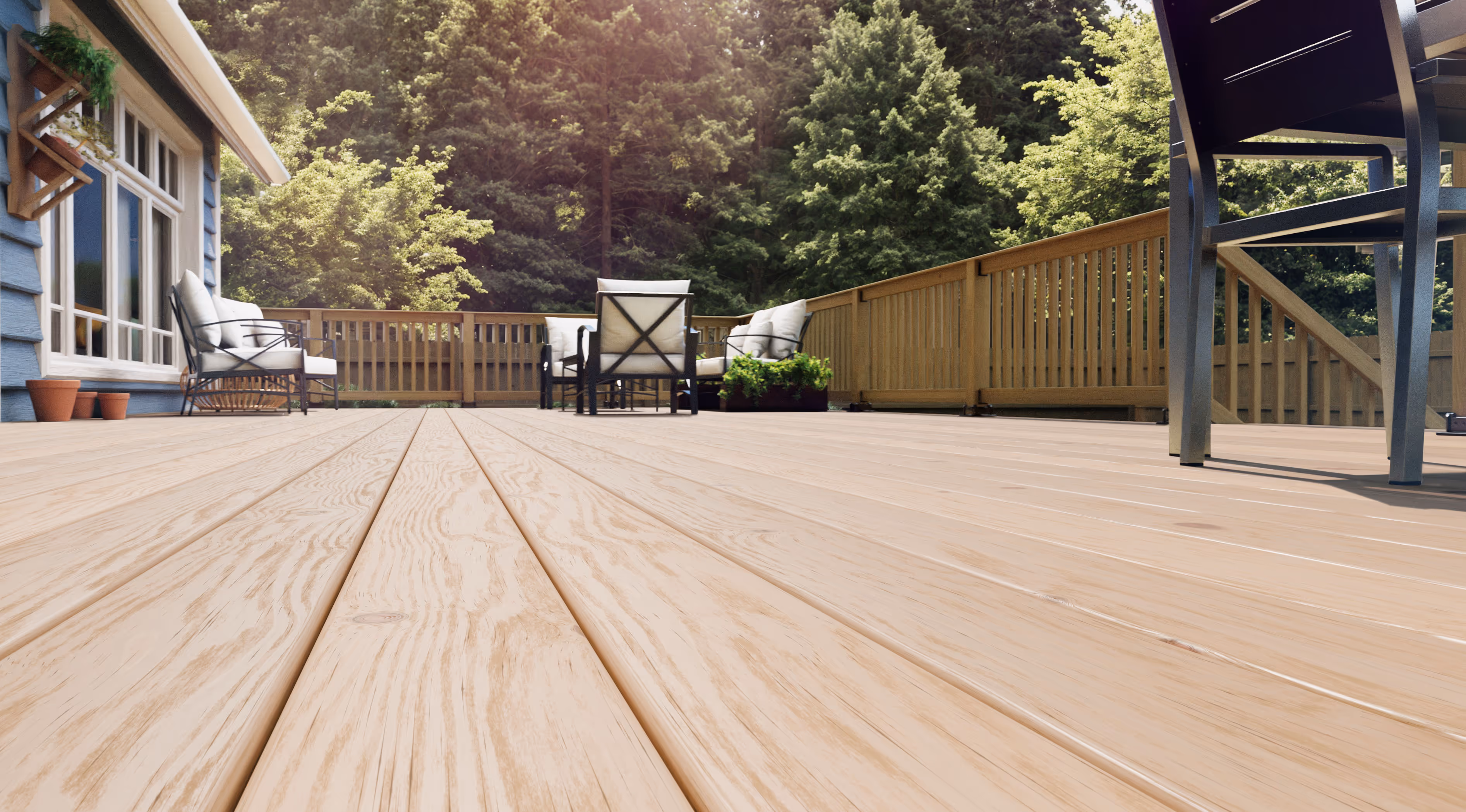Low-angle view of a spacious wooden deck with outdoor seating and a forested background.