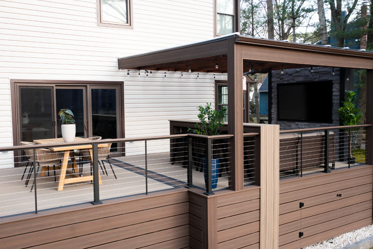 A large, white, house with a brown deck and pergola