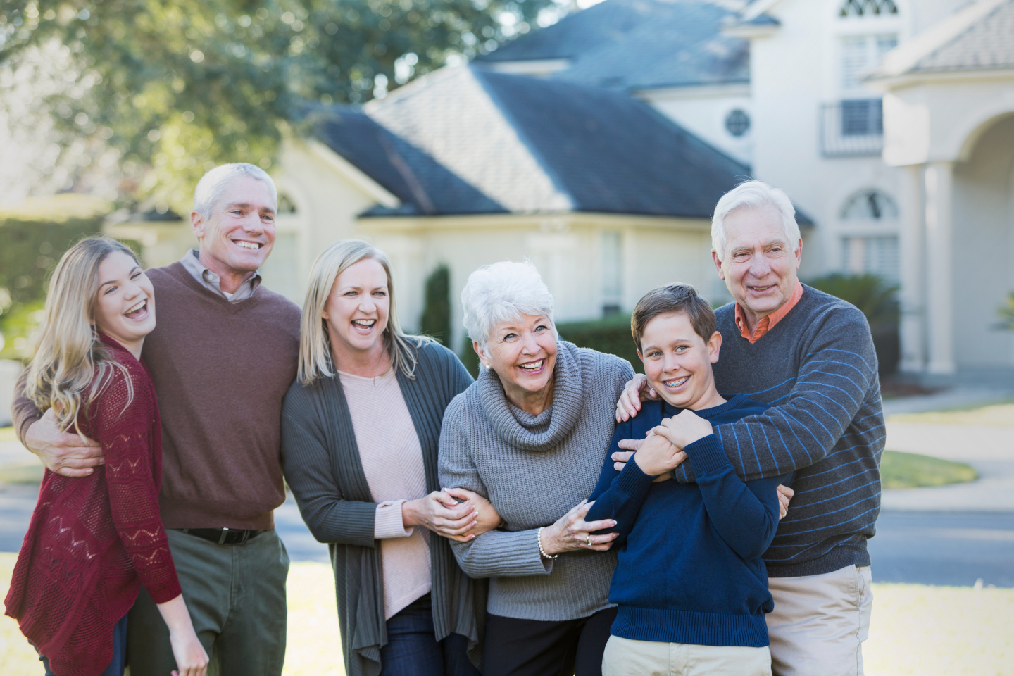 A family photograph taken outdoors, which shows a couple with their adult children and a grandchild in front of their home.