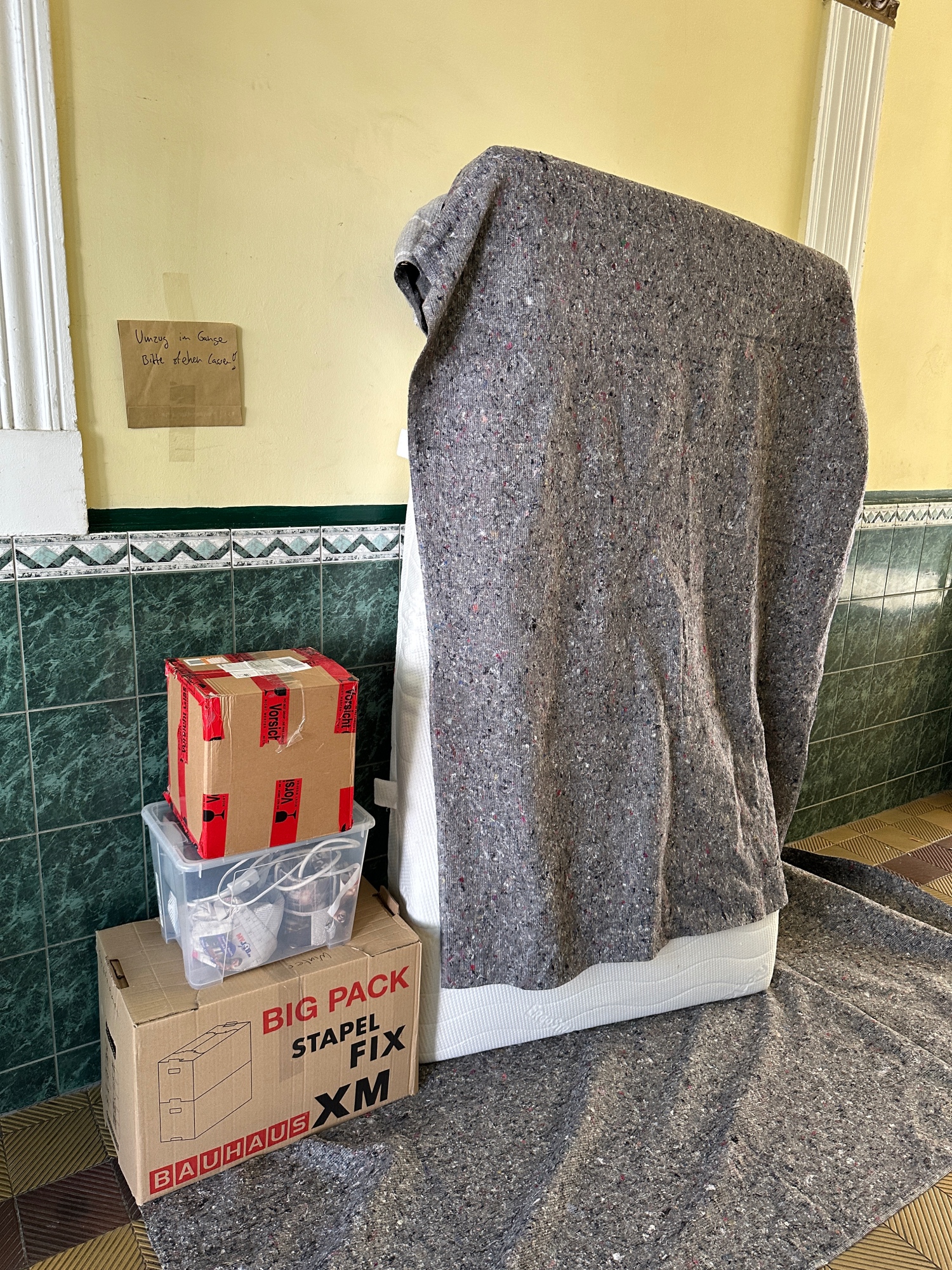 Es steht Matratze neben Umzugskartons und Packdecken in einem Berliner Hauseingang - Umzug mit Movario