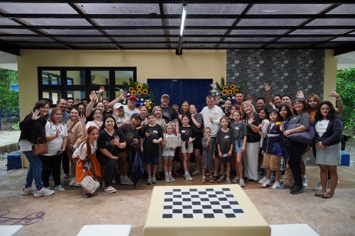 A group of people taking a celebratory photo in front of a newly built building.