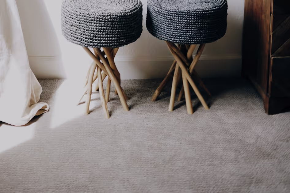 Neutral carpet beside upholstered stools in a bright room