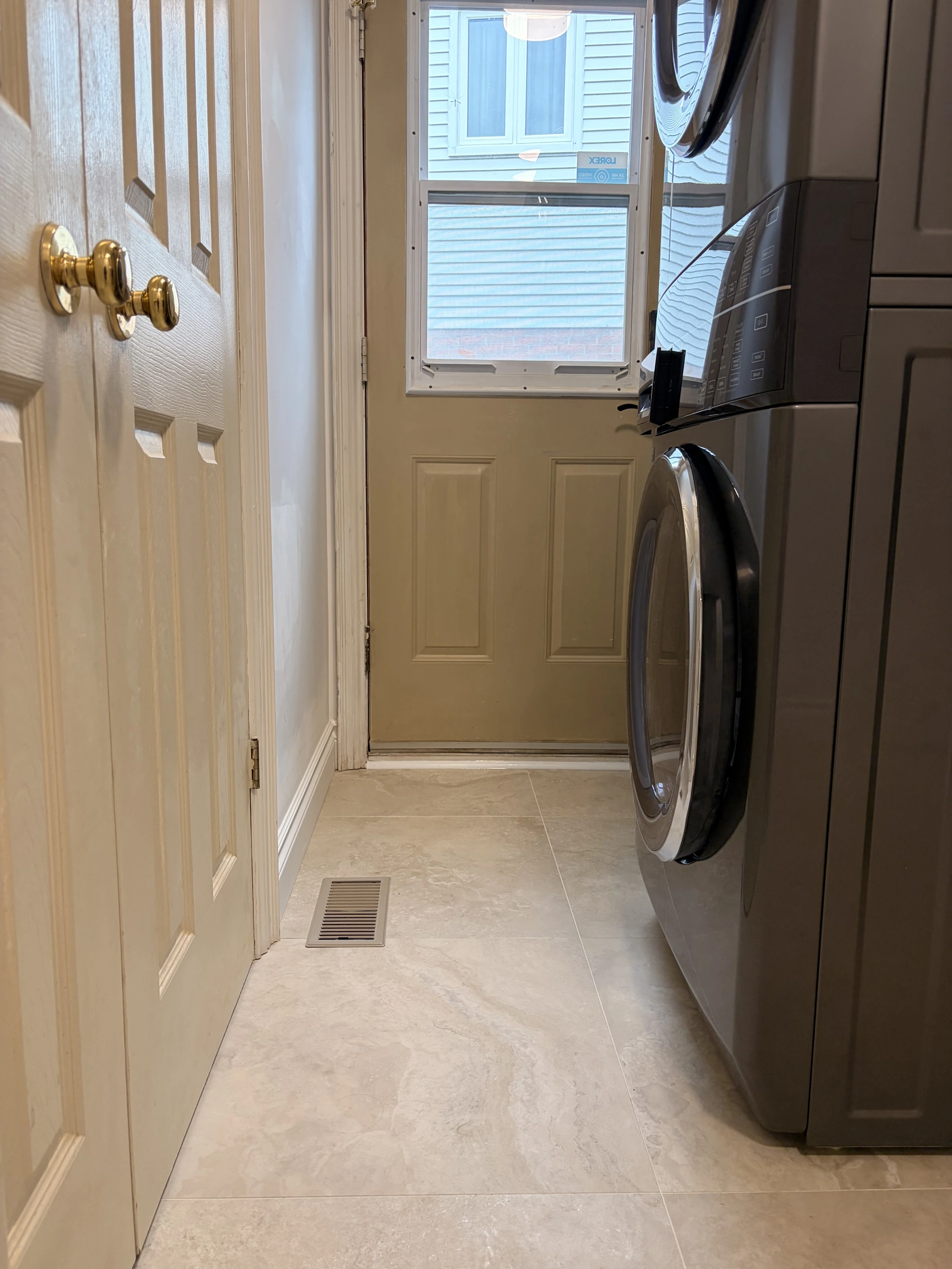 Stone-look flooring fitted around laundry appliances and a floor register