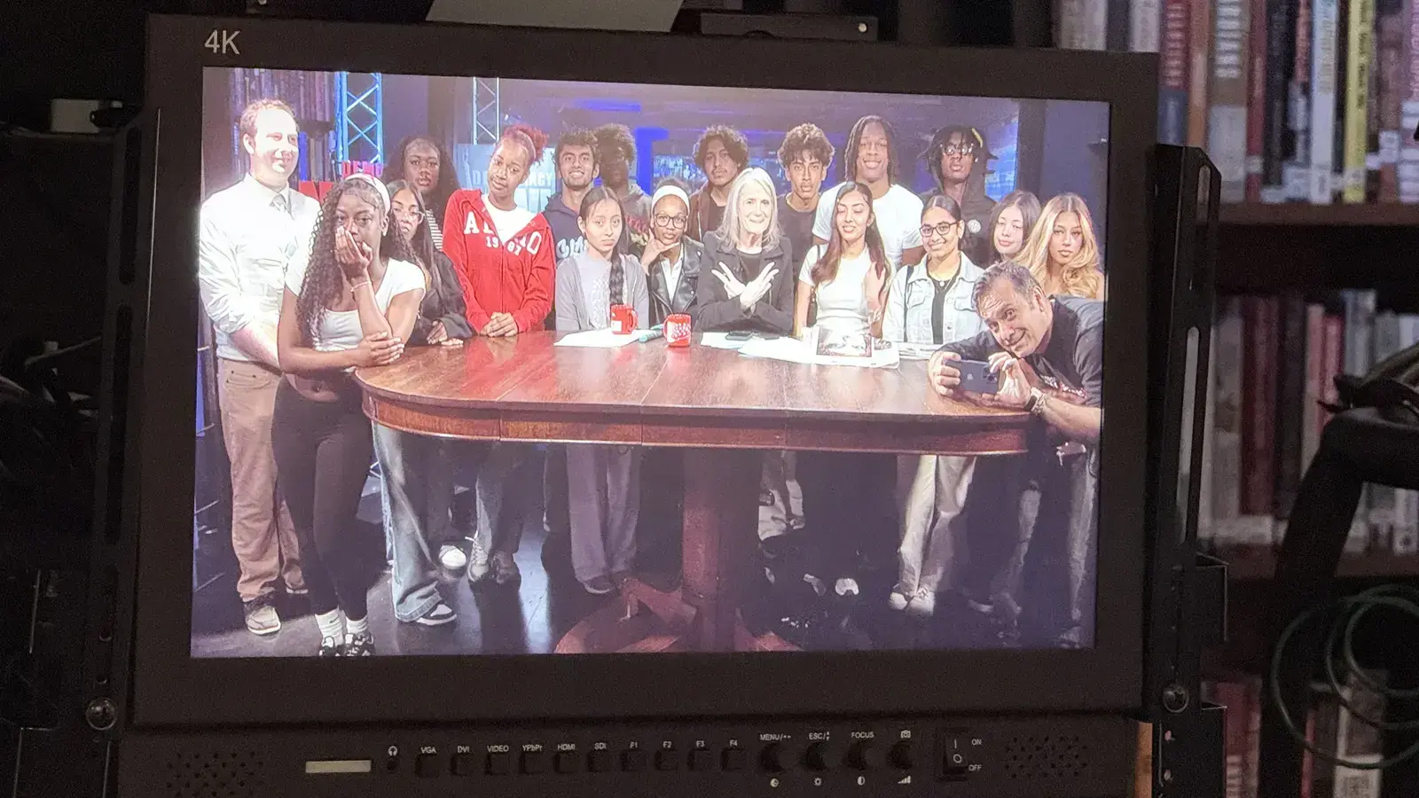 Students and adults gathered around a table on television set