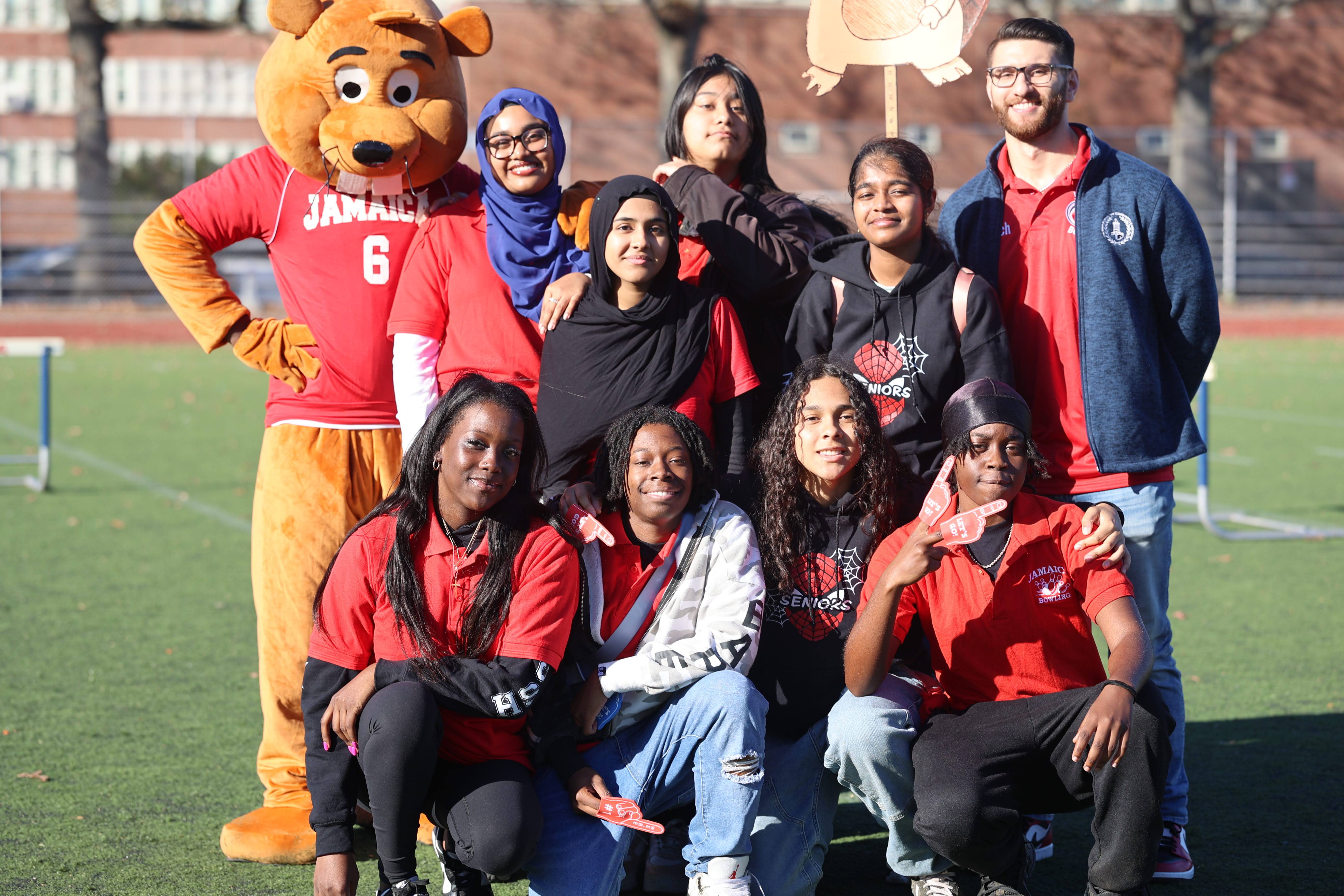 Jamaica High School students and mascot pose on athletic field