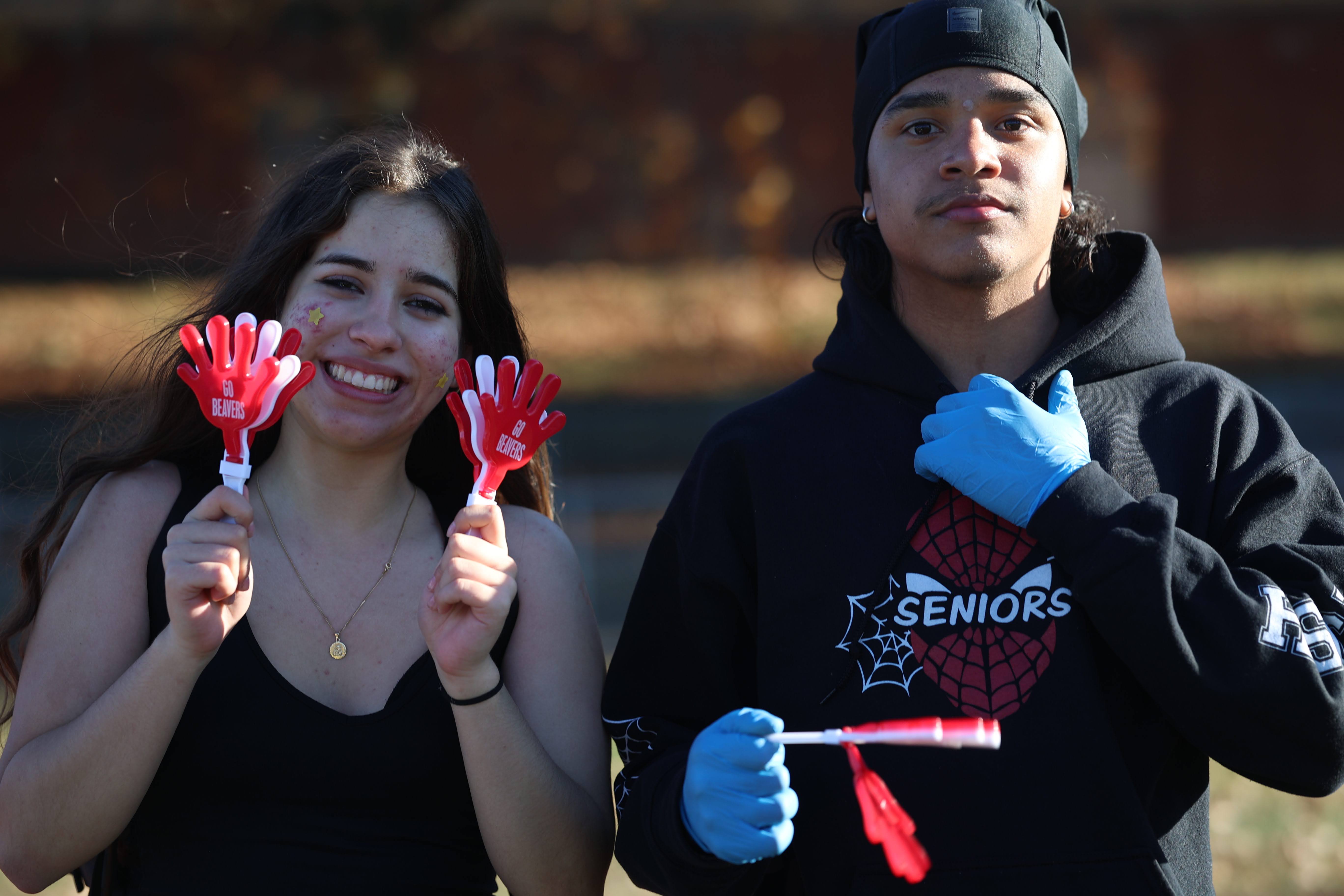 Two students holding Go Beavers clapper toys at a school event